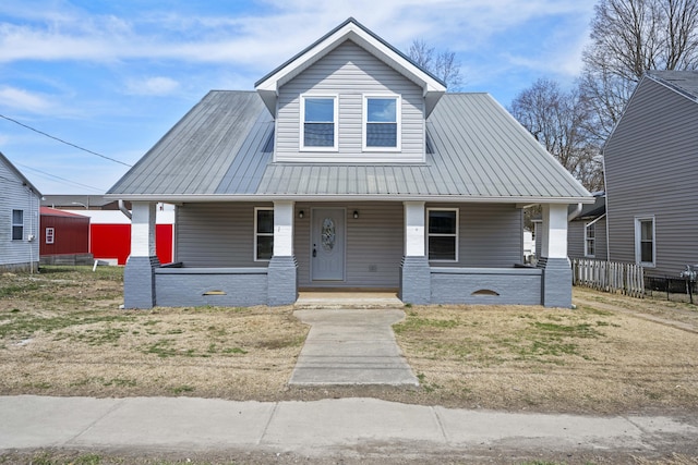 bungalow-style home with metal roof, covered porch, and fence