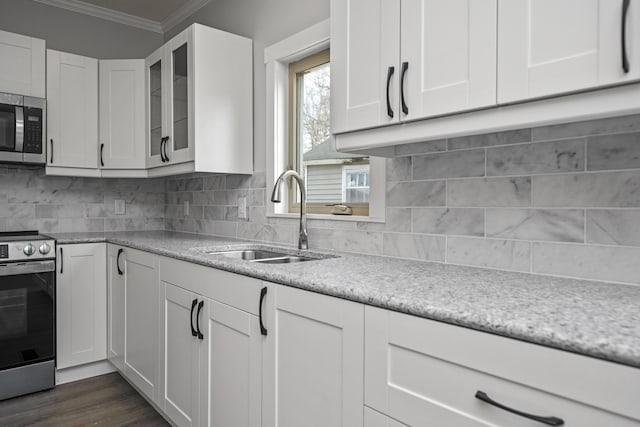 kitchen with backsplash, crown molding, white cabinets, stainless steel appliances, and a sink