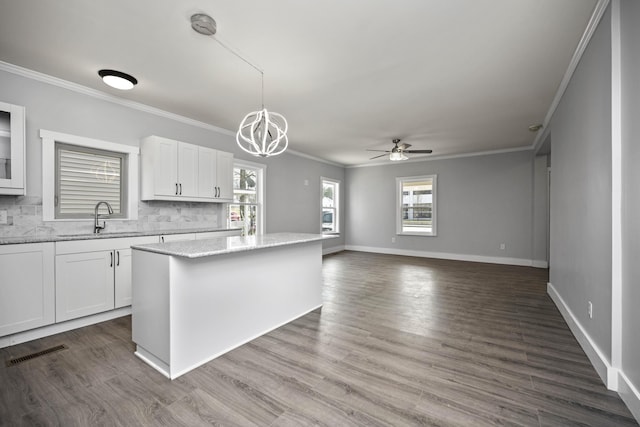 kitchen with decorative backsplash, white cabinets, visible vents, and a kitchen island