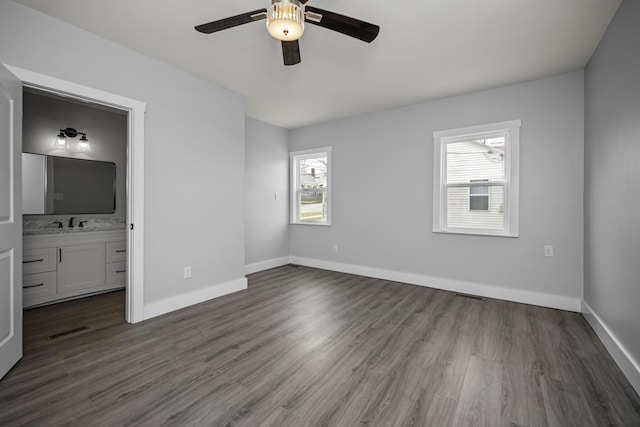 unfurnished bedroom with visible vents, baseboards, ensuite bath, and dark wood finished floors