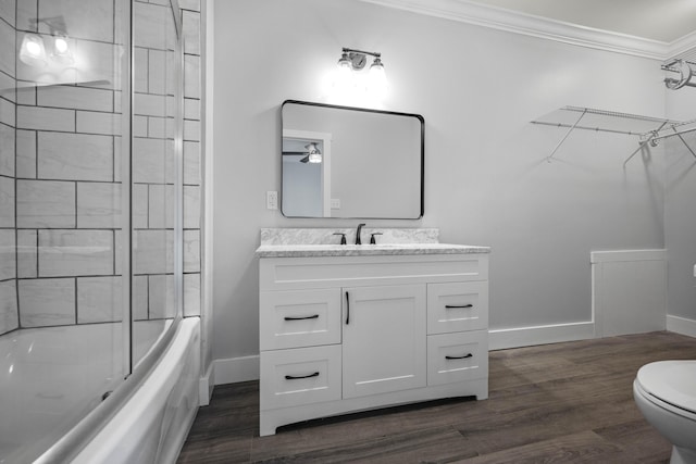 bathroom with toilet, wood finished floors, baseboards, and ornamental molding