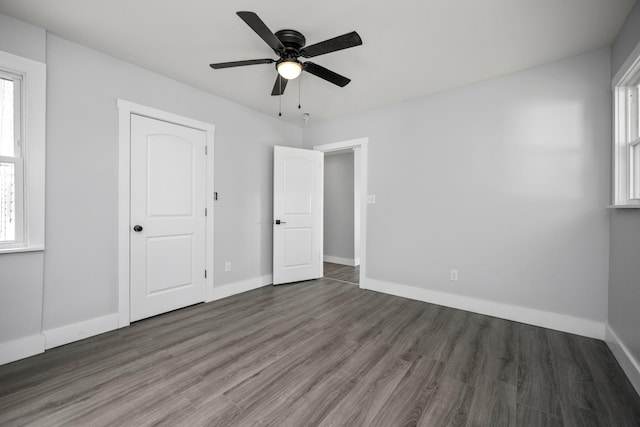 unfurnished bedroom with multiple windows, ceiling fan, baseboards, and wood finished floors