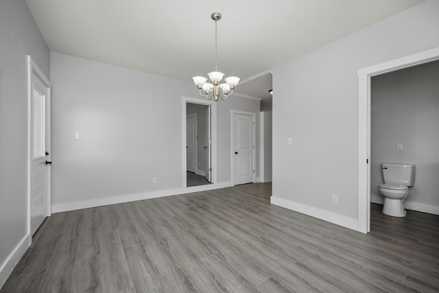 unfurnished dining area featuring a notable chandelier, wood finished floors, and baseboards