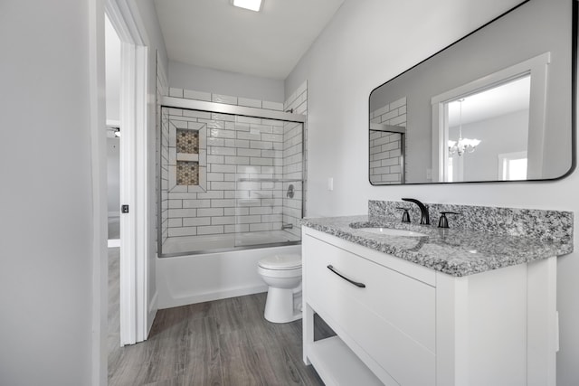 full bathroom with toilet, wood finished floors, shower / bath combination with glass door, a notable chandelier, and vanity