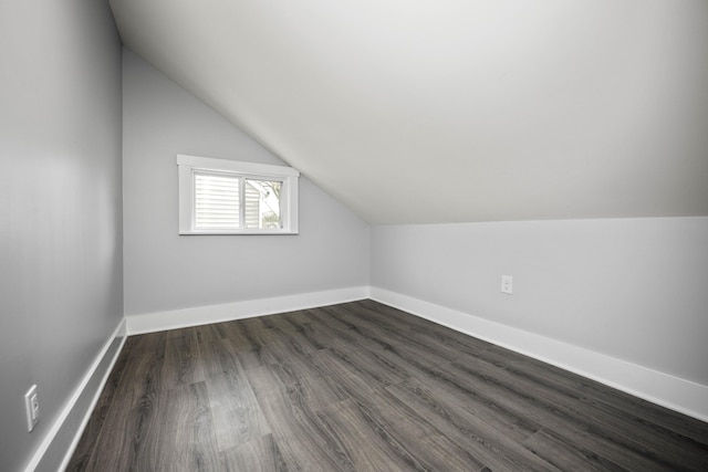 bonus room with baseboards, lofted ceiling, and dark wood finished floors