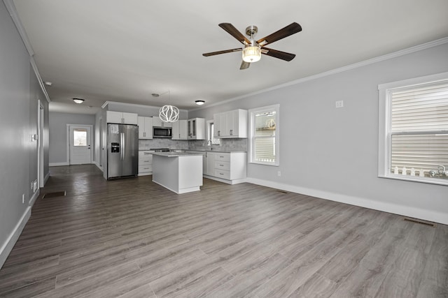 kitchen featuring visible vents, backsplash, open floor plan, appliances with stainless steel finishes, and a ceiling fan