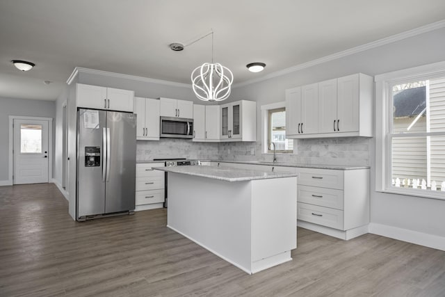 kitchen with an inviting chandelier, white cabinets, tasteful backsplash, and stainless steel appliances