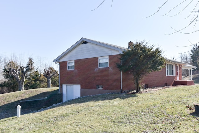 view of home's exterior with a yard, brick siding, and a chimney