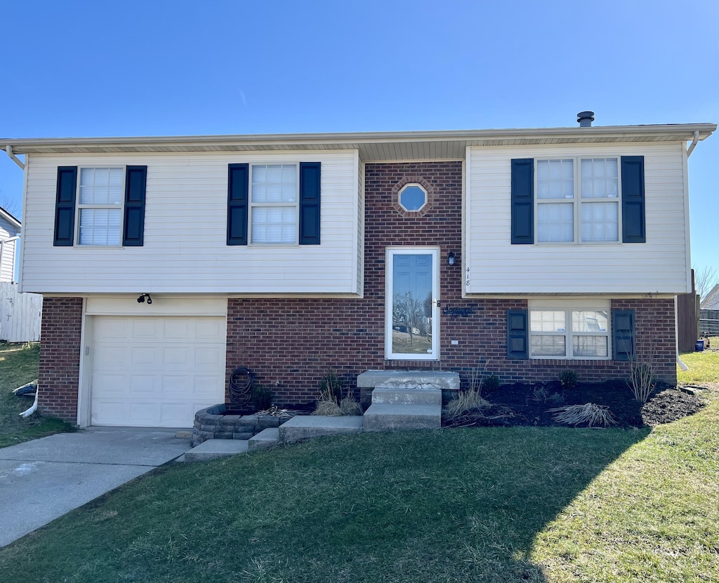 split foyer home featuring an attached garage, a front yard, concrete driveway, and brick siding