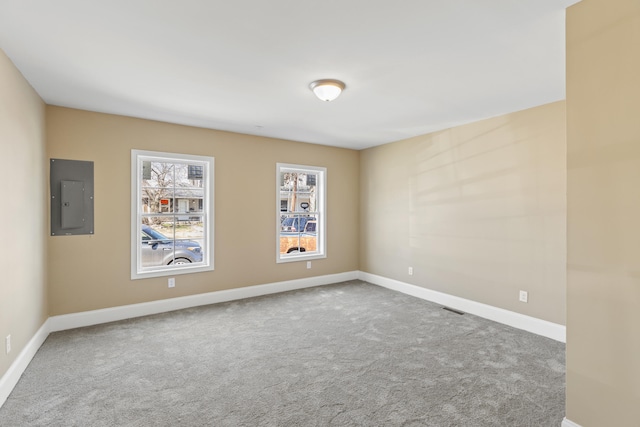 empty room with carpet floors, electric panel, visible vents, and baseboards