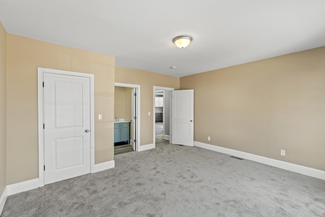 unfurnished bedroom featuring carpet, visible vents, baseboards, and ensuite bathroom