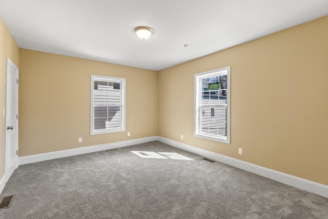 unfurnished room with carpet flooring, visible vents, and baseboards