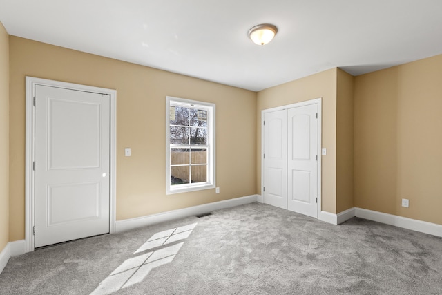 unfurnished bedroom with visible vents, a closet, baseboards, and carpet flooring