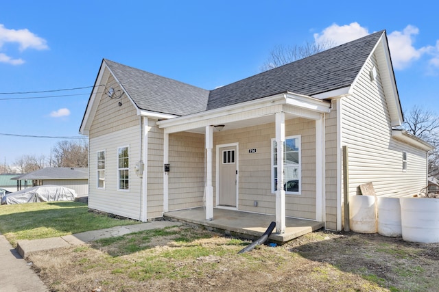 bungalow with roof with shingles, a front yard, and fence