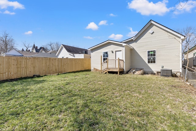 back of house featuring central AC unit, fence, and a lawn