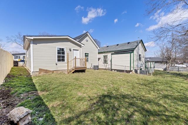 rear view of house featuring central AC, fence, and a lawn