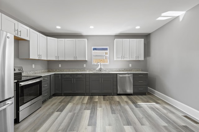 kitchen with baseboards, visible vents, light stone counters, stainless steel appliances, and a sink