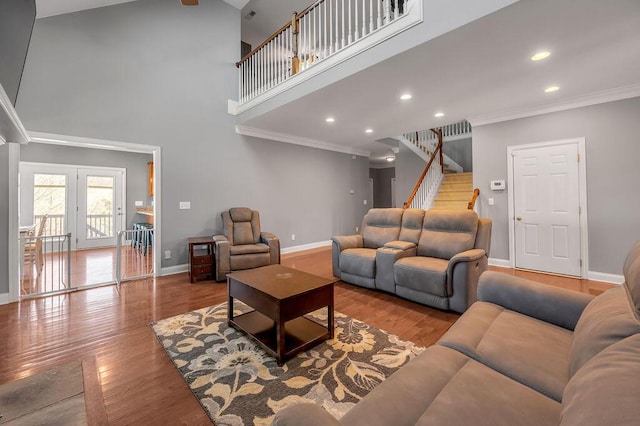 living room featuring baseboards, a high ceiling, ornamental molding, and wood finished floors