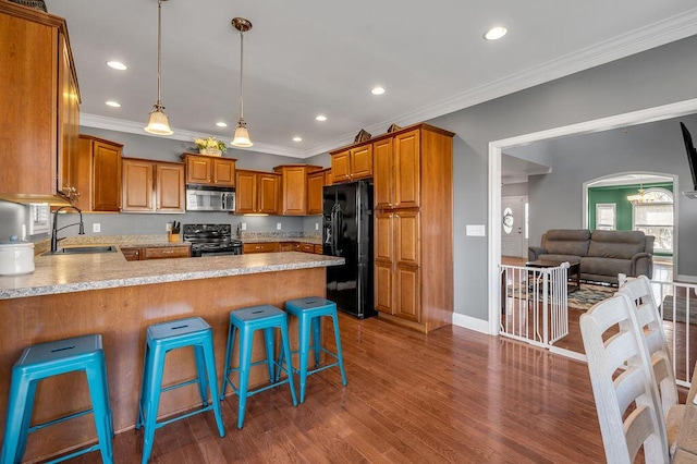 kitchen featuring arched walkways, brown cabinetry, a sink, a peninsula, and black appliances