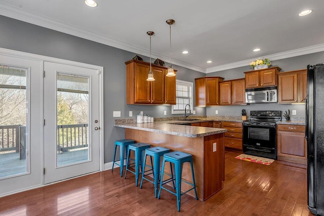 kitchen featuring dark wood-style floors, brown cabinetry, a sink, a peninsula, and black appliances