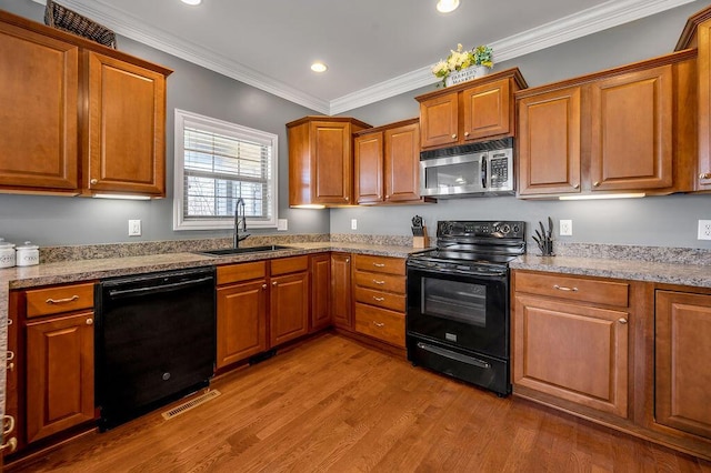 kitchen featuring brown cabinets, visible vents, a sink, and black appliances