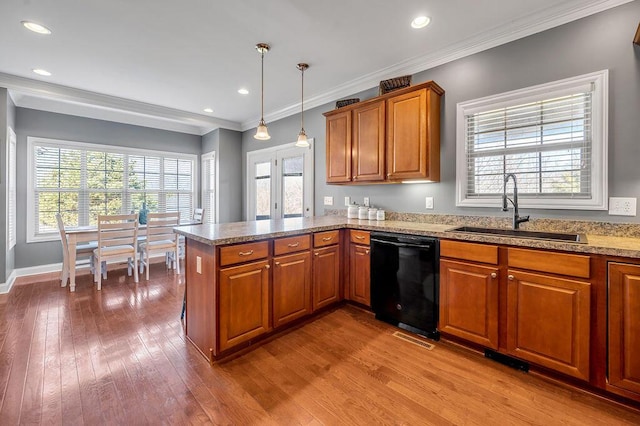 kitchen featuring dishwasher, brown cabinets, hardwood / wood-style floors, a peninsula, and a sink