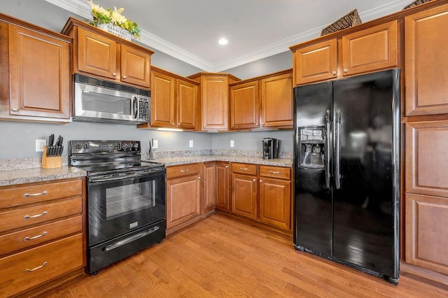 kitchen featuring black appliances, brown cabinetry, and crown molding