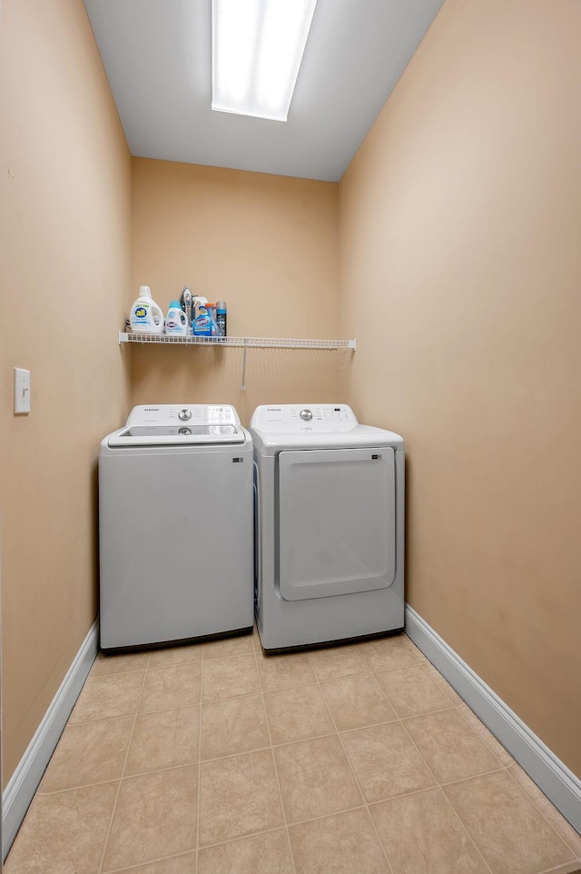 washroom featuring light tile patterned floors, laundry area, baseboards, and washer and dryer