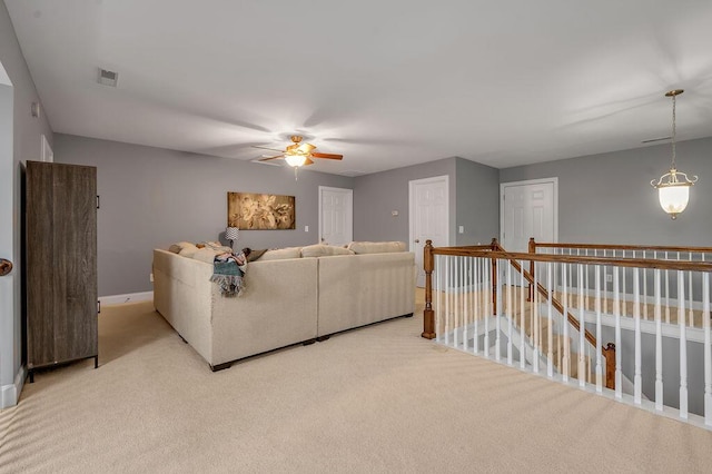 living room with baseboards, ceiling fan, visible vents, and light colored carpet