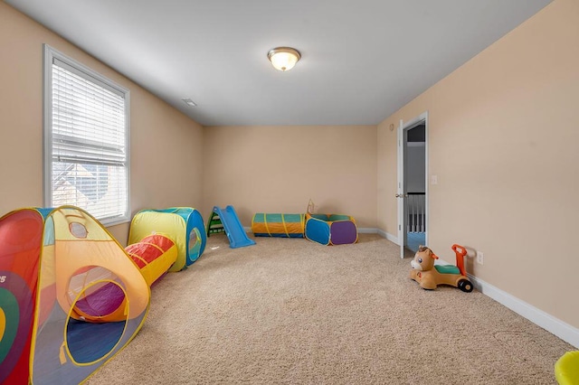 recreation room with baseboards and carpet flooring