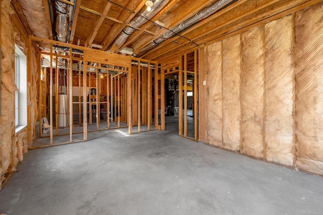 misc room featuring water heater and unfinished concrete flooring