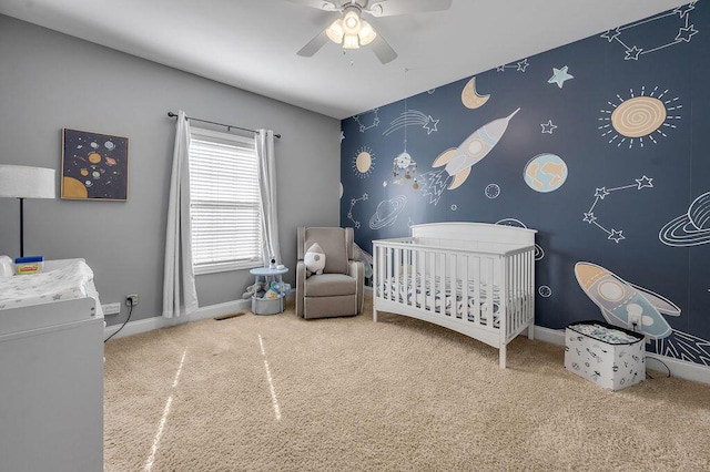 bedroom with a crib, visible vents, baseboards, a ceiling fan, and carpet floors