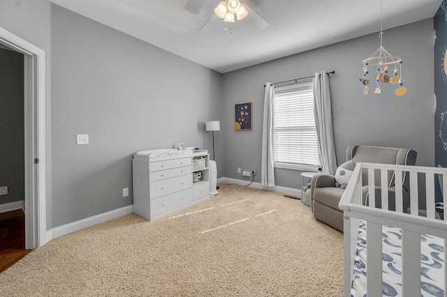 bedroom with a ceiling fan, a nursery area, carpet, and baseboards