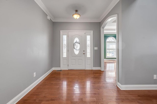 entrance foyer with baseboards, arched walkways, wood finished floors, and ornamental molding