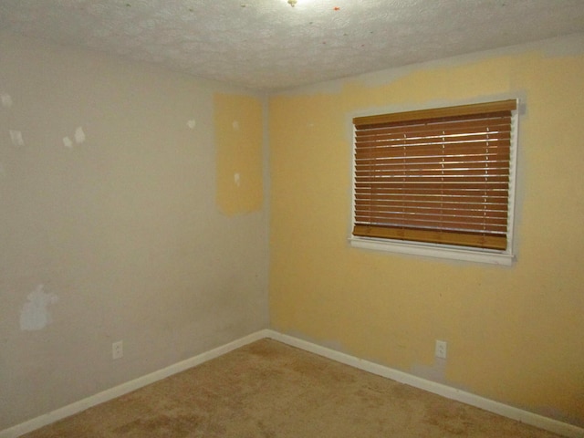 carpeted spare room with a textured ceiling and baseboards