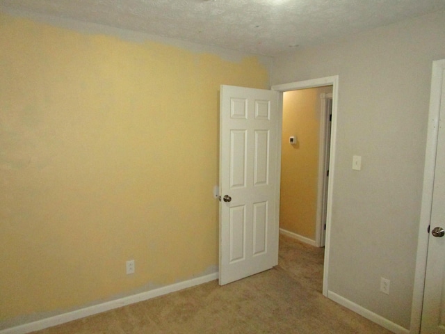 spare room featuring light carpet and baseboards