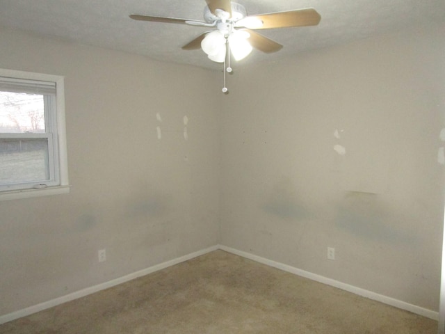 carpeted spare room with ceiling fan and baseboards