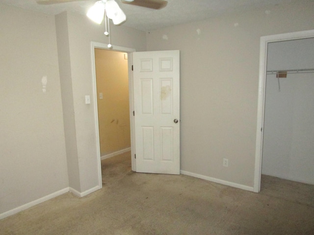 unfurnished bedroom featuring carpet floors, a closet, baseboards, and a ceiling fan