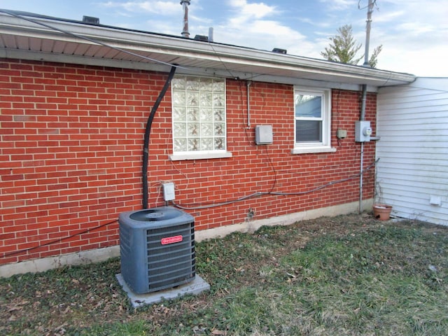 view of side of property featuring central air condition unit and brick siding