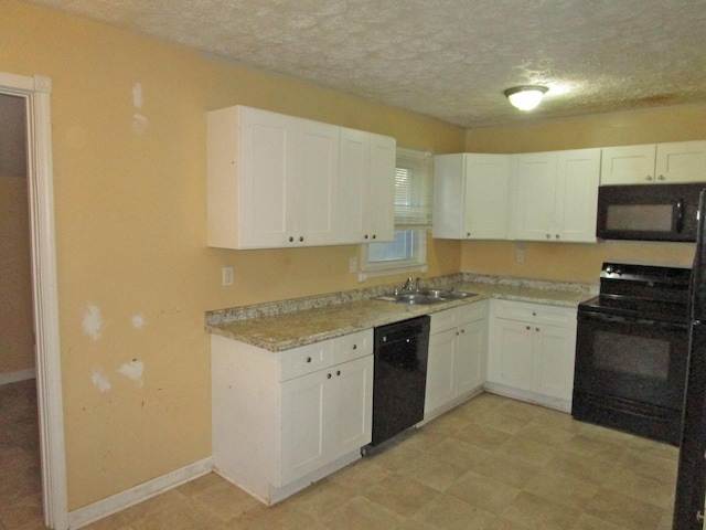 kitchen featuring light countertops, a textured ceiling, black appliances, white cabinetry, and a sink