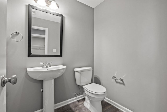 bathroom featuring toilet, a sink, baseboards, and wood finished floors