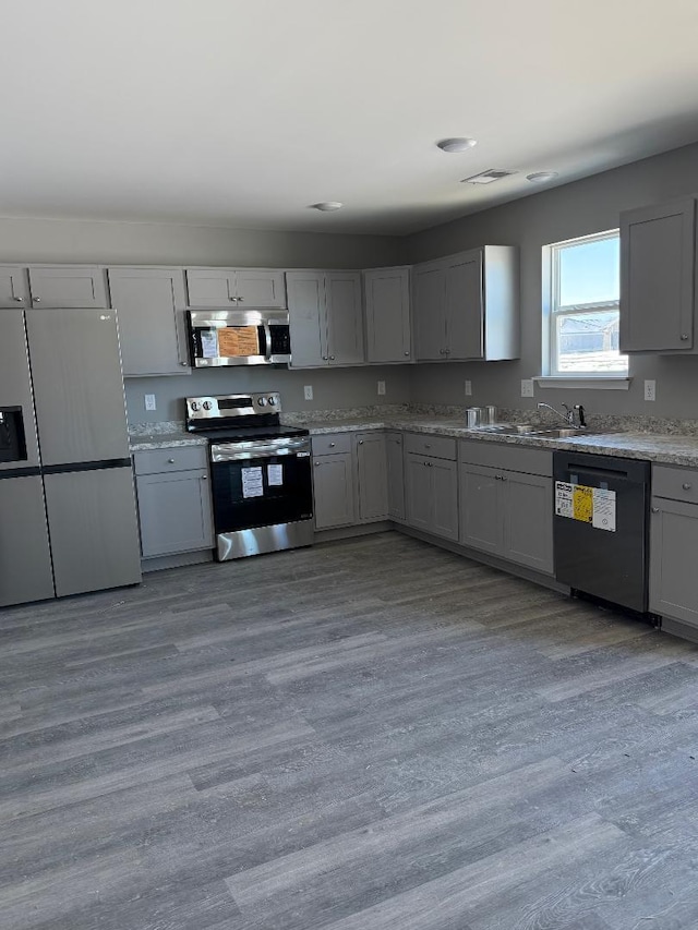 kitchen featuring appliances with stainless steel finishes, a sink, visible vents, and gray cabinetry