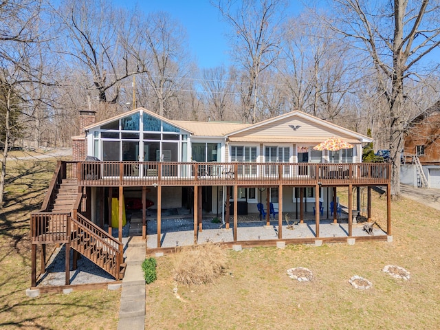 back of property with a yard, a wooden deck, stairs, and a patio