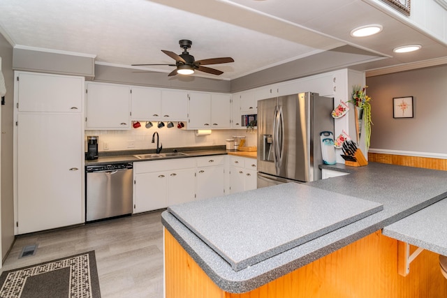 kitchen with crown molding, ceiling fan, appliances with stainless steel finishes, a peninsula, and a sink