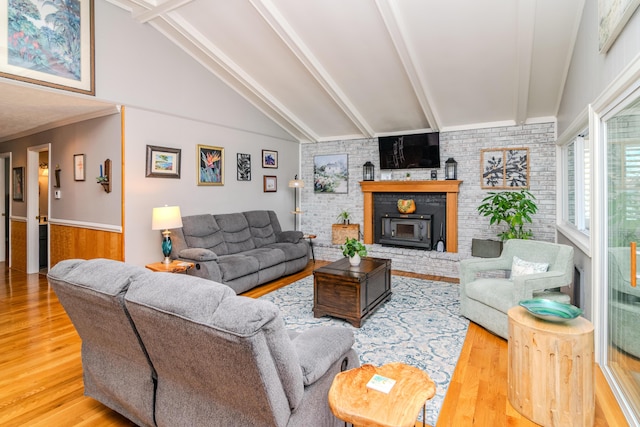 living area featuring a fireplace, lofted ceiling with beams, and wood finished floors