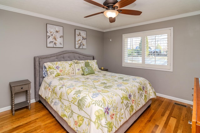 bedroom featuring visible vents, wood finished floors, and ornamental molding