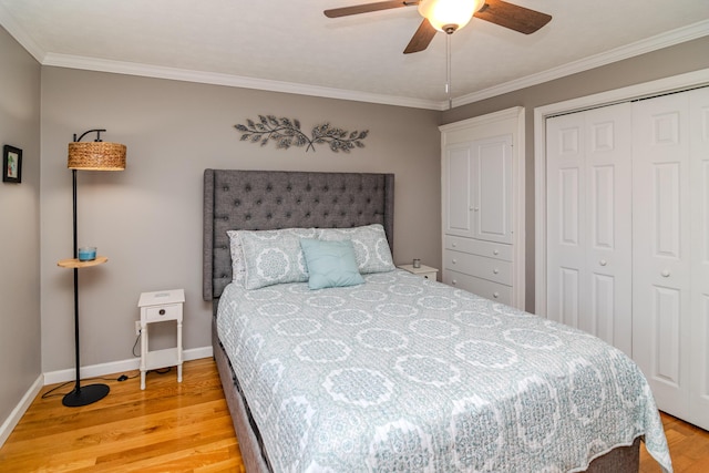 bedroom with a closet, baseboards, light wood-style flooring, and ornamental molding