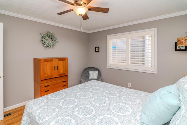 bedroom featuring light wood-type flooring, visible vents, baseboards, and crown molding