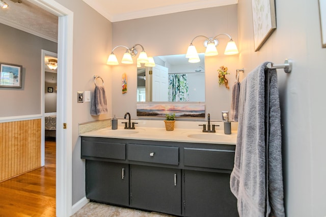 full bath featuring a sink, double vanity, wood finished floors, and crown molding