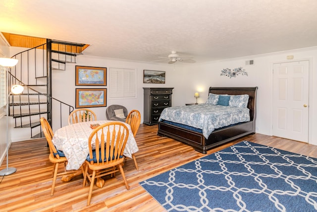 bedroom with visible vents, a textured ceiling, and wood finished floors